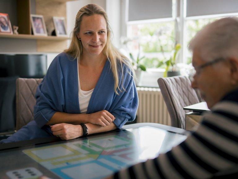 Eine Mitarbeiterin hört einer Bewohnerin lächelnd beim Erzählen zu.